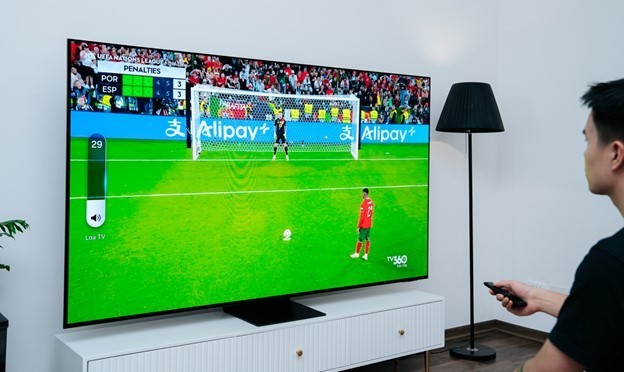 A person watching a football game on a televisionDescription automatically generated